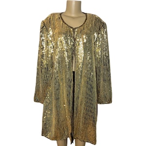May include: A long-sleeved, open-front jacket covered in vertical rows of shimmering gold sequins. The garment features a rounded neckline, a straight hemline, and a structured shoulder design, creating a uniform, reflective metallic appearance.