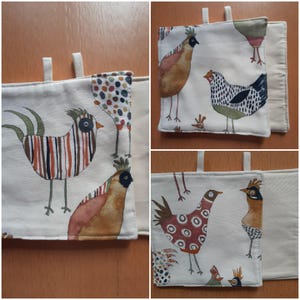 Könnte beinhalten: Ein Set aus drei Topflappen aus cremefarbenem Stoff mit einem skurrilen Hühnerdesign. Jeder Topflappen zeigt eine andere Hühnerillustration in Braun-, Rot- und Grüntönen. Die Topflappen haben eine Schlaufe zum Aufhängen.