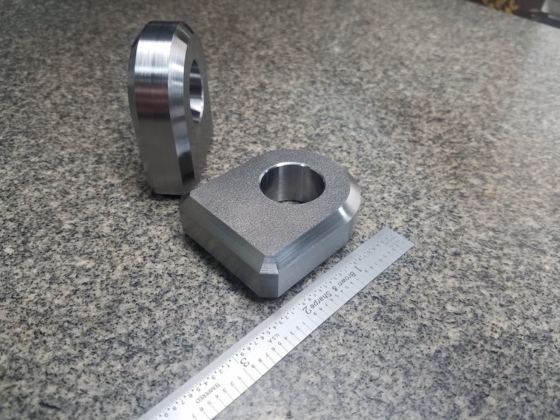 Puede incluir: Dos anillos de metal plateado con un acabado liso. Los anillos son de diferentes tama&ntilde;os y tienen un agujero en el centro. Una regla est&aacute; en el fondo.