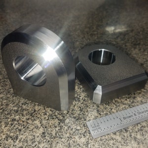 Puede incluir: Dos anillos de elevaci&oacute;n de metal, uno con forma redondeada y el otro con forma cuadrada. Ambos tienen un agujero central para un gancho de elevaci&oacute;n.