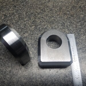 Puede incluir: Dos anillos met&aacute;licos, uno con un agujero redondo y el otro con forma de D, se muestran junto a una regla. La regla est&aacute; marcada con pulgadas y el texto "Brown & Sharpe 2".