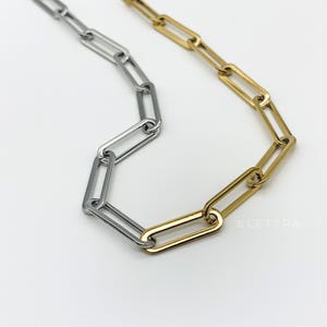 May include: A silver and gold chain necklace with a linked chain design. The chain is made of two different metals, with the silver links alternating with the gold links.