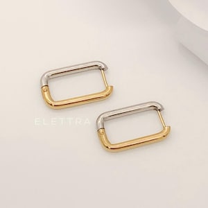 May include: Two rectangular hoop earrings. Each earring is a combination of silver and gold tones. The silver portion is at the top, and the gold portion is at the bottom. The earrings are on a white background. The word "ELETTRA" is printed in the image.
