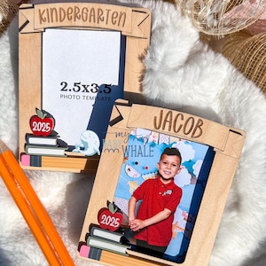 May include: Two wooden photo frames with a pencil and stack of books design. The top frame says "Kindergarten" and has a 2.5x3.5 photo template. The bottom frame says "Jacob" and has a photo of a young boy in a red shirt. Both frames have the year 2025 on them.