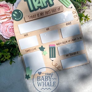 May include: Wooden first day of school sign with the name "TRIPP" in green and white. The sign includes spaces to write the date, age, height, things loved, and what the child wants to be when they grow up. A pencil and stars are also featured.
