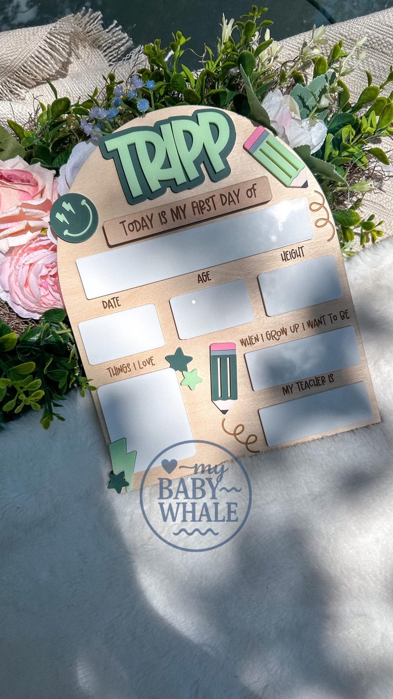 May include: Wooden first day of school sign with the name "TRIPP" in green and white. The sign includes spaces to write the date, age, height, things loved, and what the child wants to be when they grow up. A pencil and stars are also featured.