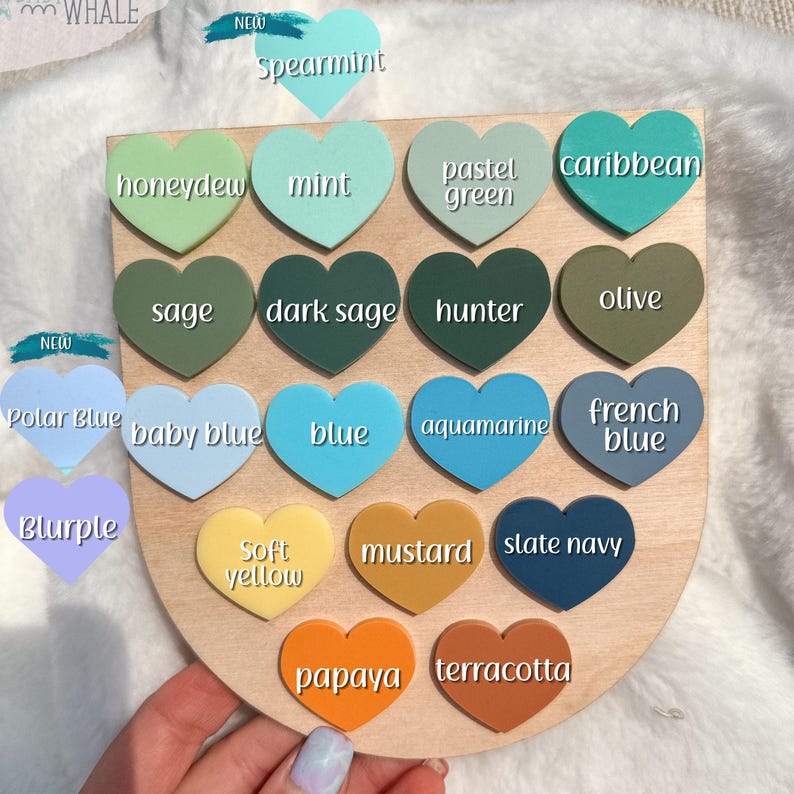 May include: A wooden color chart featuring heart-shaped color swatches in various shades. Colors include spearmint, honeydew, mint, pastel green, caribbean, sage, dark sage, hunter, olive, polar blue, baby blue, blue, aquamarine, french blue, blurple, soft yellow, mustard, slate navy, papaya, and terracotta.