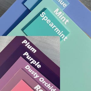May include: A layered arrangement of color swatches in shades of blue, green, purple, and pink. Each swatch is labeled with a color name in white text, including "Blurple," "Polar blue," "Mint," "Spearmint," "Plum," "Purple," "Dusty Orchid," "Rose," and "Hibiscus."