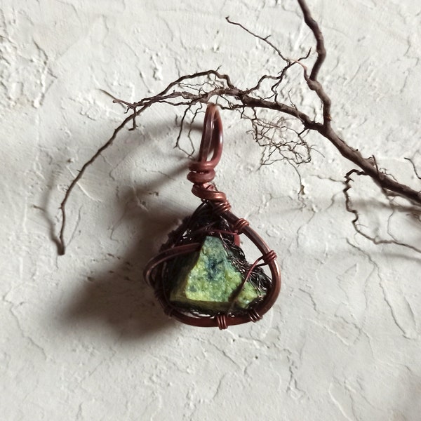 Green serpentinite pendant composed in copper wire net. Handmade artistic craft with calming, relaxing gemstone. Nested crystal collection