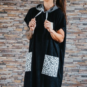 May include: A black hooded towel with a leopard print pocket. The towel is made of a soft, absorbent material and is perfect for drying off after a swim or shower.
