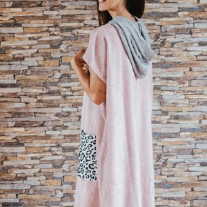 May include: A pink hooded towel with a leopard print pocket. The towel is made of soft, absorbent material and is perfect for drying off after a shower or swim.