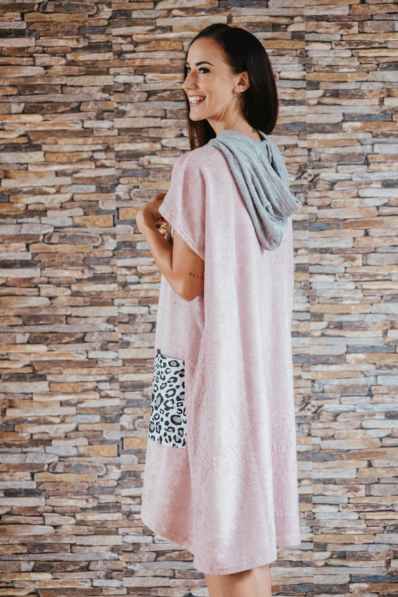 May include: A pink hooded towel with a leopard print pocket. The towel is made of soft, absorbent material and is perfect for drying off after a shower or swim.
