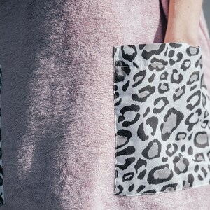 May include: A pink terry cloth robe with two large pockets. The pockets have a white and black leopard print.