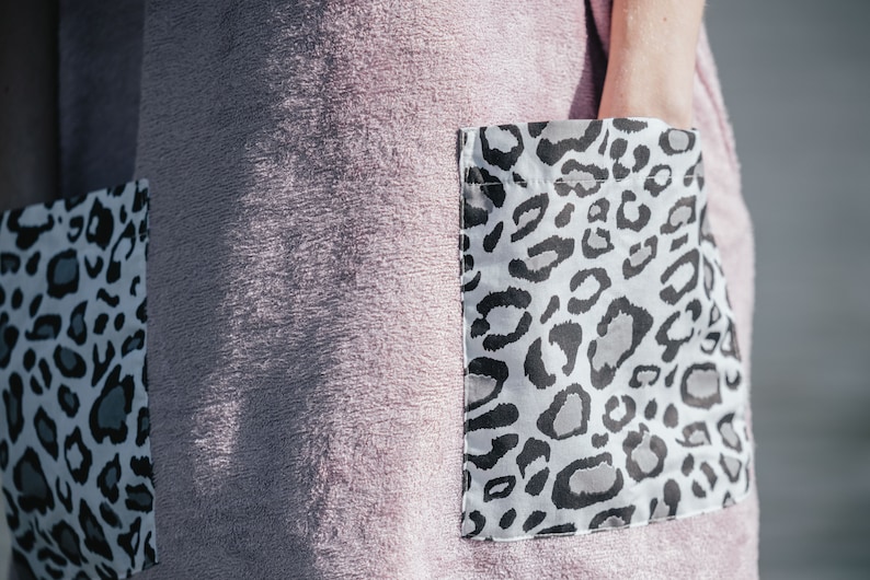 May include: A pink terry cloth robe with two large pockets. The pockets have a white and black leopard print.
