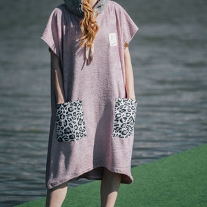 May include: A pink hooded towel with leopard print pockets. The towel is made of a soft, absorbent material and is perfect for drying off after a swim or shower.