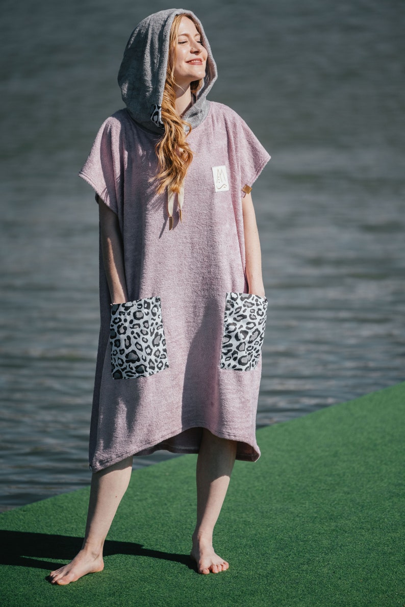 May include: A pink hooded towel with leopard print pockets. The towel is made of a soft, absorbent material and is perfect for drying off after a swim or shower.