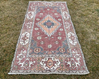 May include: A vintage rug with a red, orange, and blue geometric pattern. The rug has a white border with intricate designs.