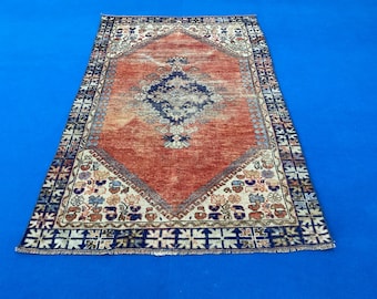 Könnte beinhalten: Ein Vintage-Teppich mit einem geometrischen Muster in Rot, Creme und Blau. Der Teppich hat einen Fransenrand und ist aus Wolle.