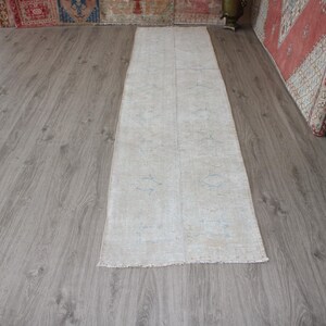 May include: A white runner rug with a subtle pattern. The rug is laid out on a wood floor.