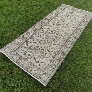 Peut inclure: Un tapis beige et brun &agrave; motifs g&eacute;om&eacute;triques. Le tapis est pos&eacute; sur une surface herbeuse verte.