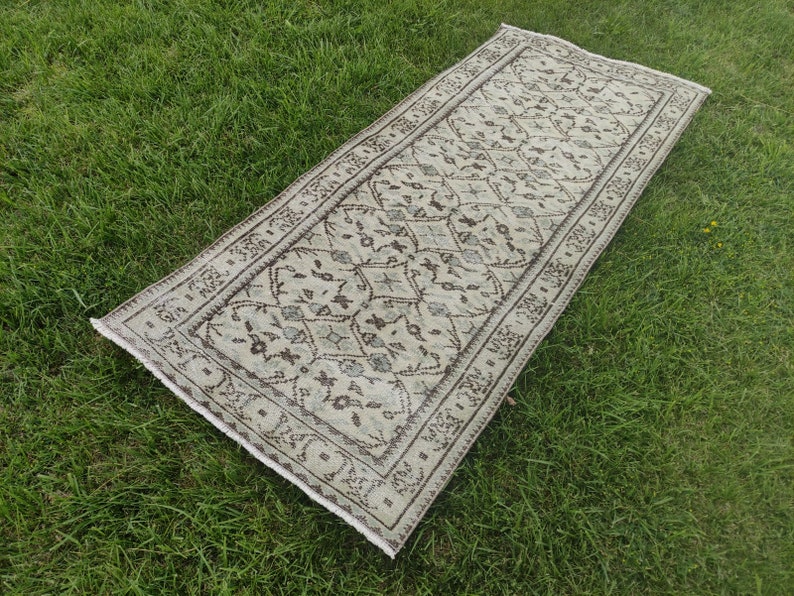 Peut inclure: Un tapis beige et brun &agrave; motifs g&eacute;om&eacute;triques. Le tapis est pos&eacute; sur une surface herbeuse verte.