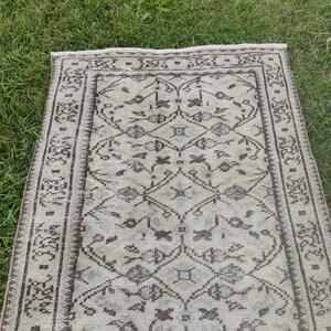 Peut inclure: Un tapis de couloir vintage avec un fond cr&egrave;me et un motif g&eacute;om&eacute;trique brun. Le tapis a une bordure &agrave; franges.