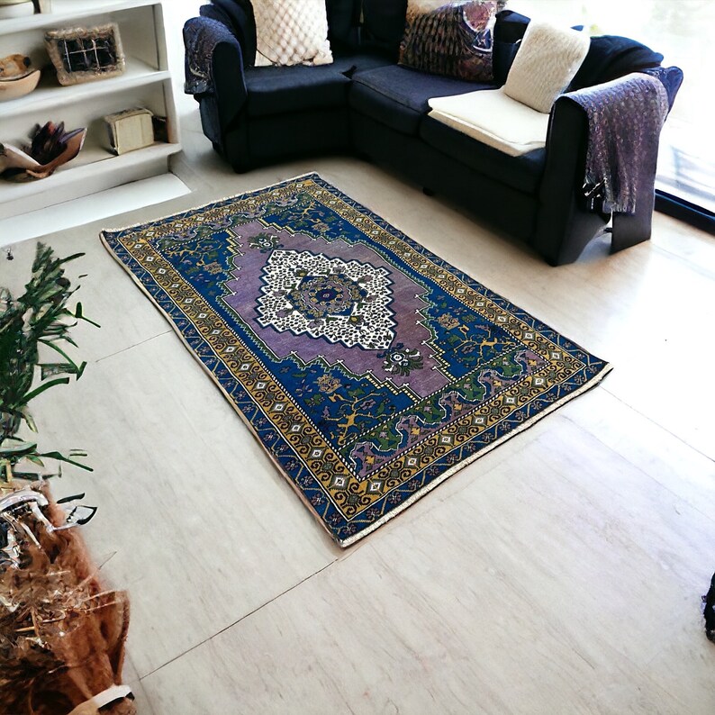 May include: A vintage style rug with a purple, blue, and yellow floral pattern. The rug has a cream-colored border.