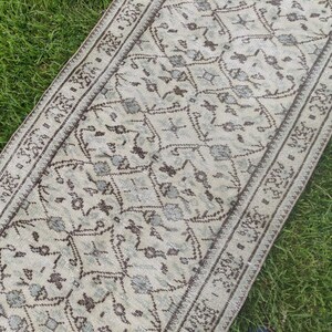 Peut inclure: Un tapis de couloir blanc et brun &agrave; motifs g&eacute;om&eacute;triques. Le tapis a une bordure &agrave; franges.