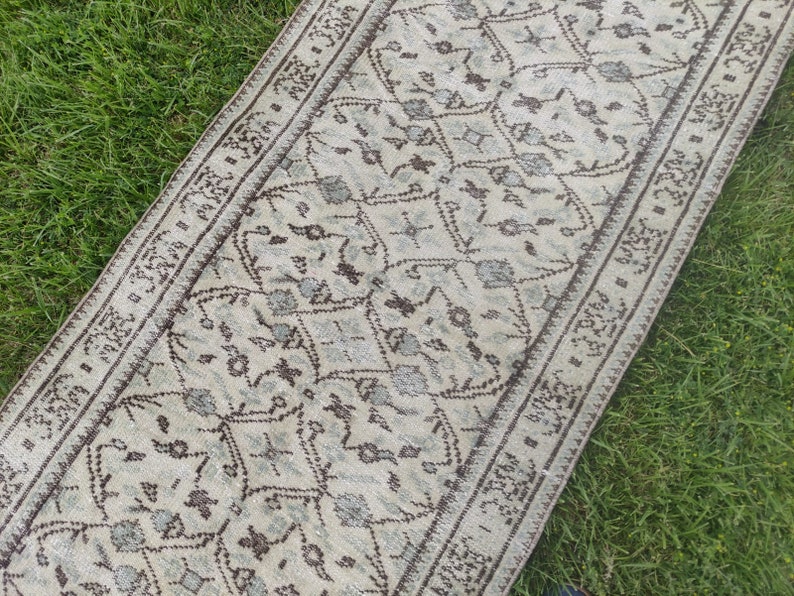 Peut inclure: Un tapis de couloir blanc et brun &agrave; motifs g&eacute;om&eacute;triques. Le tapis a une bordure &agrave; franges.