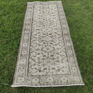 Peut inclure: Un tapis de couloir vintage avec un fond cr&egrave;me et un motif floral brun. Le tapis a une bordure frang&eacute;e.