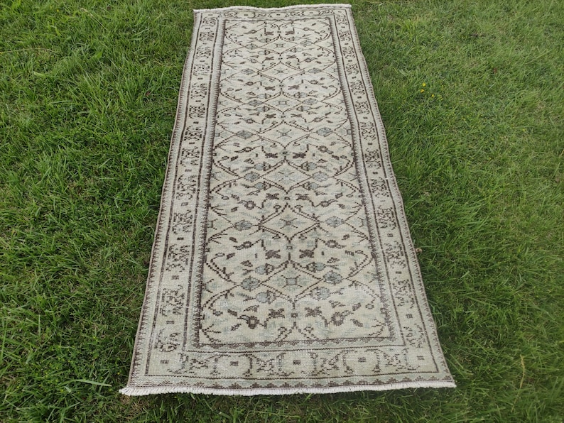 Peut inclure: Un tapis de couloir vintage avec un fond cr&egrave;me et un motif floral brun. Le tapis a une bordure frang&eacute;e.
