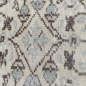 Peut inclure: Gros plan sur un tapis beige avec un motif floral r&eacute;p&eacute;titif brun et bleu.