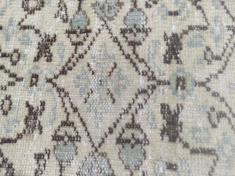 Peut inclure: Gros plan sur un tapis beige avec un motif floral r&eacute;p&eacute;titif brun et bleu.