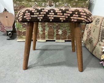 May include: A small wooden stool with a woven seat cushion in brown and pink. The stool has a rustic look and is perfect for adding a touch of bohemian style to any room.