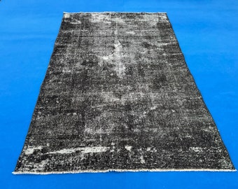 May include: A black and white distressed rug with a faded, vintage look. The rug has a fringed edge and is made of a soft, woven material.