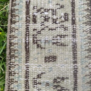 Peut inclure: Gros plan sur un tapis beige et brun &agrave; motifs avec une bordure &agrave; franges. Le tapis pr&eacute;sente un motif traditionnel avec des formes g&eacute;om&eacute;triques et des motifs floraux.