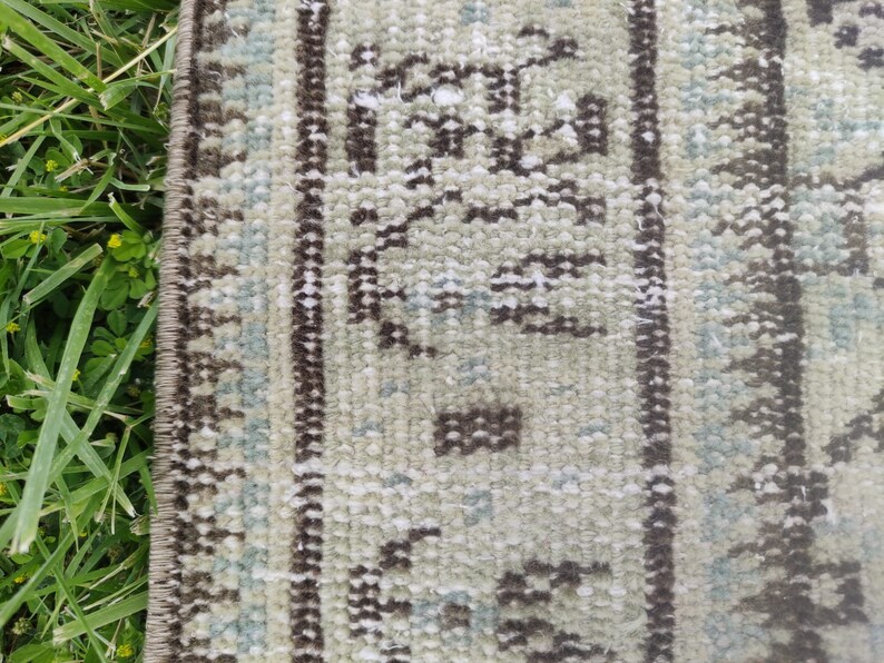 Peut inclure: Gros plan sur un tapis beige et brun &agrave; motifs avec une bordure &agrave; franges. Le tapis pr&eacute;sente un motif traditionnel avec des formes g&eacute;om&eacute;triques et des motifs floraux.
