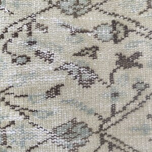 Peut inclure: Gros plan sur un tapis beige avec un motif floral dans les tons de brun et de bleu.