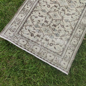 Peut inclure: Un tapis de couloir de style vintage avec un fond beige clair et un motif g&eacute;om&eacute;trique brun et bleu. Le tapis a une bordure frang&eacute;e.