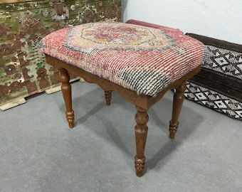 May include: A wooden stool with turned legs and a red, white, and black patterned cushion. The cushion is made of woven fabric and has a geometric design.