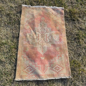 May include: A vintage rug with a faded pink and beige color scheme. The rug has a traditional Persian design with a central medallion and intricate floral patterns.