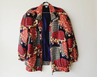 May include: A red, blue, and cream patterned jacket with a zipper closure. The jacket has a patchwork design with floral and geometric patterns.