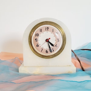 Reloj de repisa eléctrico Art Déco de latón ónix blanco de los años 30. Reloj de piedra curva con diseño aerodinámico antiguo. Reloj de sobremesa con diseño llamativo en crema jaspeada.