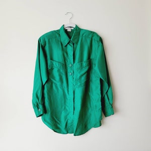 May include: A long-sleeved, emerald green button-down shirt with a collared neckline and two patch pockets.