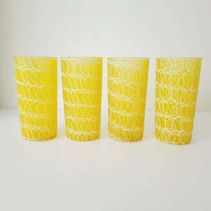 May include: Set of four yellow glass tumblers with a white woven pattern. The glasses are clear and have a textured surface.