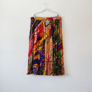 May include: A colorful, pleated skirt with a vibrant abstract pattern. The skirt features a mix of red, yellow, green, and purple hues. The design includes various shapes and patterns, creating a unique and eye-catching garment.