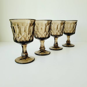 May include: Set of four brown glass stemmed goblets with a diamond pattern.