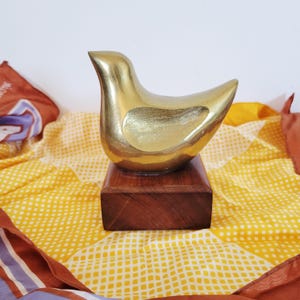 Estatueta de pomba em latão maciço: Objeto de arte escultural em estilo meados do século XX, com base de madeira assinada.