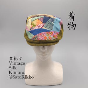 May include: A flat cap featuring a patchwork top made of various colorful silk fabric scraps with floral and geometric patterns. The sides and brim are made of olive green corduroy fabric. Text on the image includes 着物, #花々, Vintage Silk Kimono, @SatoRikko.