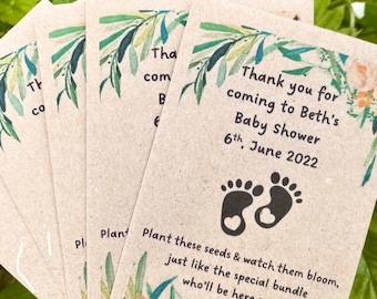 以下が含まれることがあります： 茶色の紙製のサンキューカードで、花柄のデザインと「Bethのベビーシャワーにお越しいただきありがとうございます 6月6日 2022」というテキストが書かれています。カードには、ハートが描かれた足跡が2つあります。「これらの種を植えて、特別な束がすぐにここに来るように、花が咲くのを見てください。」というテキストもカードに書かれています。